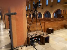 Blick hinter die Kulissen: Möglichst dezenter Aufbau einer der Kameras im Kirchenschiff, darunter Teile der Tontechnik. (Foto: bewegtbildwerft)