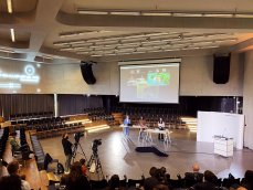 Blick in den Saal der hybriden Konferenz: Das Präsenzpublikum sieht auf der großen Leinwand bewusst die gleiche Ansicht, die auch die digital zugeschalteten Teilnehmer auf ihren Endgeräten sehen. (Foto: bewegtbildwerft)